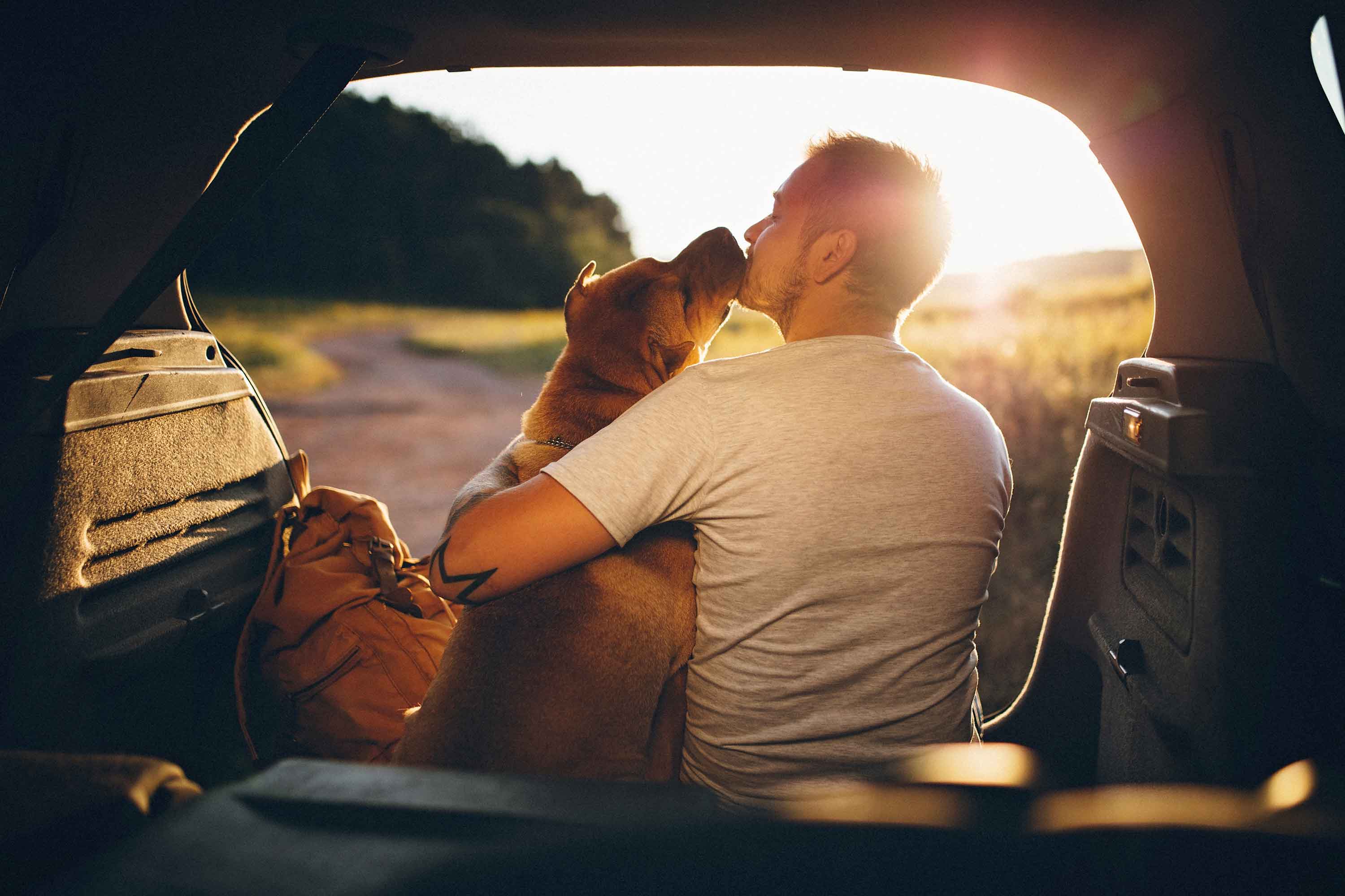 man sitting in trunk with his dog - man zit in koffer met zijn hond